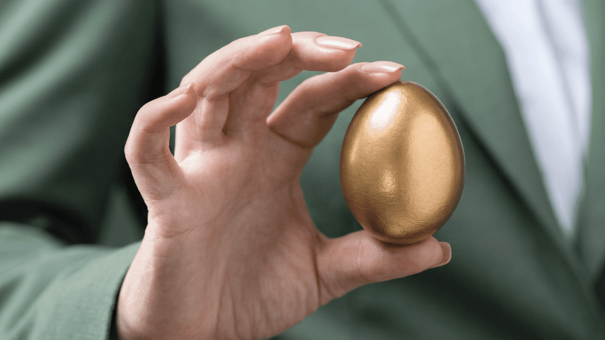 A hand carefully cradles a golden egg, symbolizing a protected nest egg.
