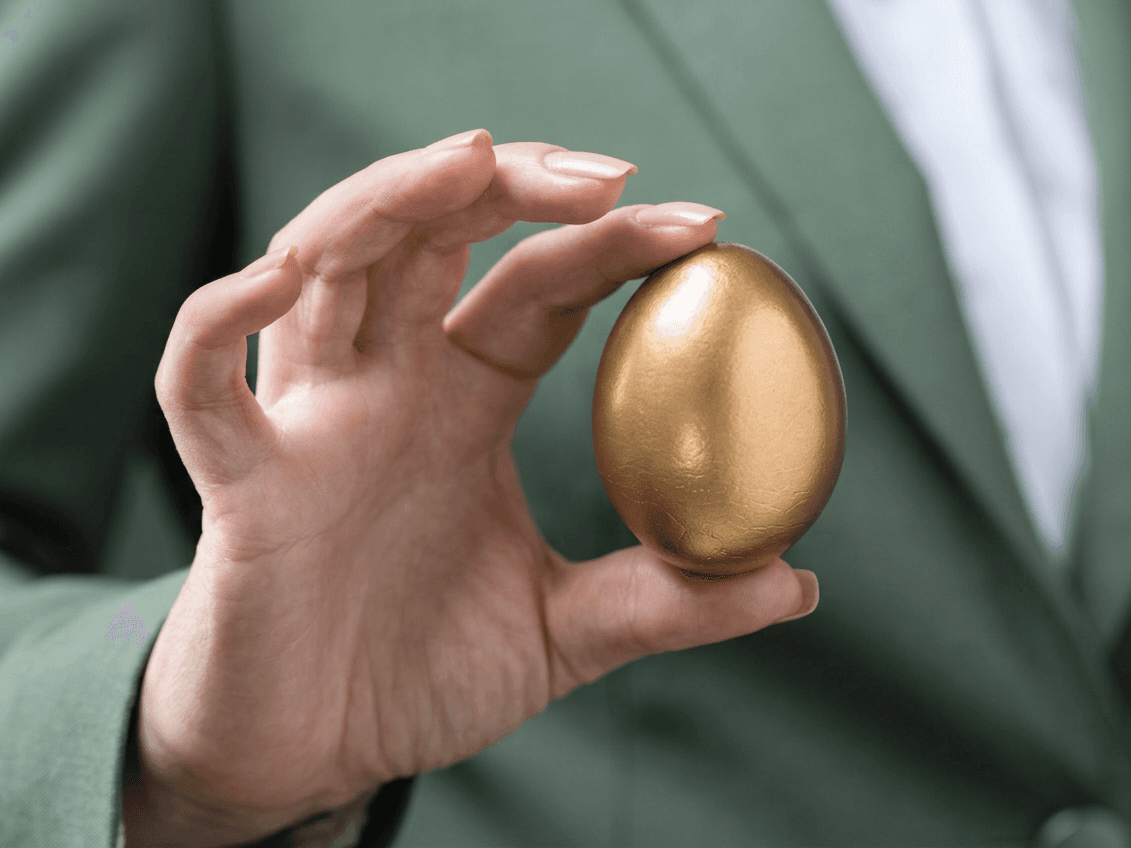 A hand carefully cradles a golden egg, symbolizing a protected nest egg.